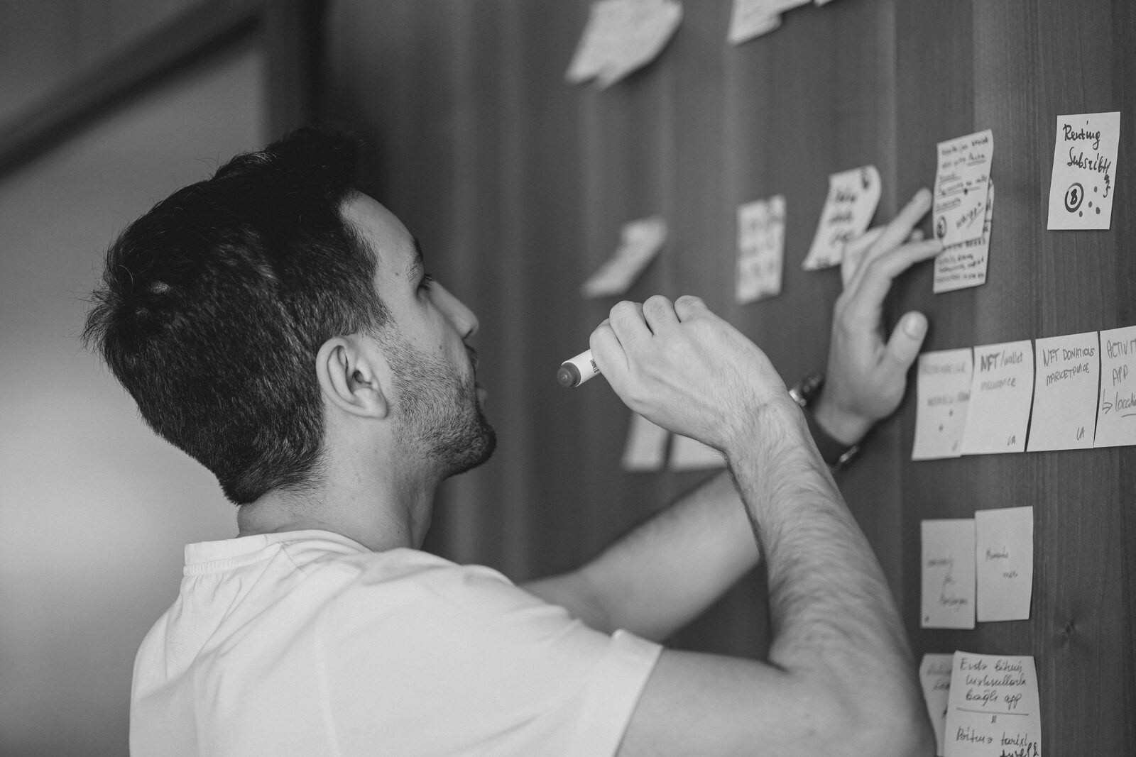 Un entrepreneur organise sa stratégie à l’aide de post-it sur un mur
